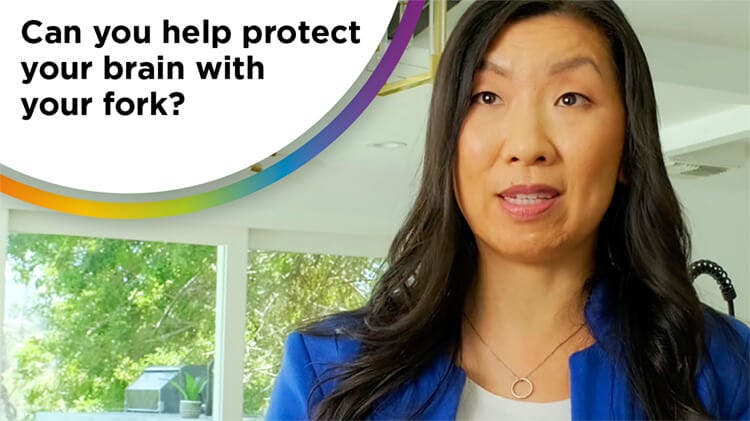 Photo of a dark-haired woman wearing a white shirt and blue blazer with the text “can you help protect your brain with your fork?”