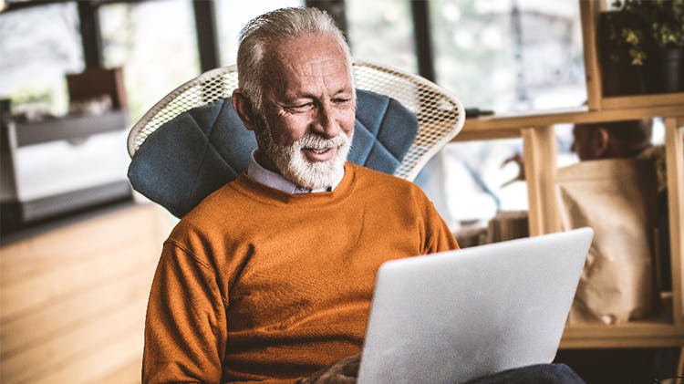 Older man on chair using laptop
