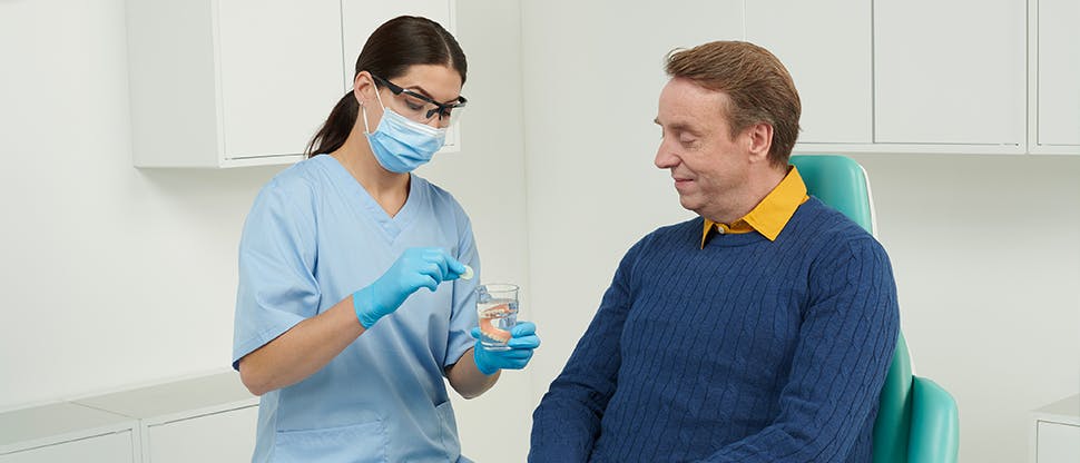 David, paciente con prótesis dental hablando con un odontólogo