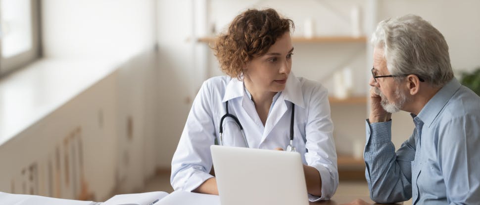 Paciente adulto mayor recibiendo consejo de una doctora