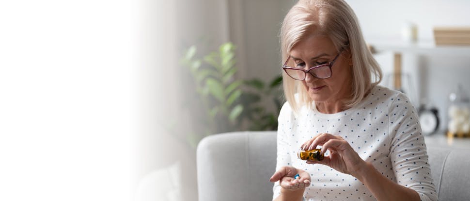 Mujer adulta usando gafas tomando su medicina diaria.