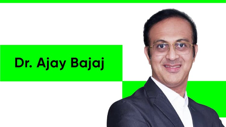 Foto del Dr. Ajay Bajaj, un hombre asiático con cabello corto y oscuro. Lleva gafas, una camisa de rayas rojas y blancas y una chaqueta negra