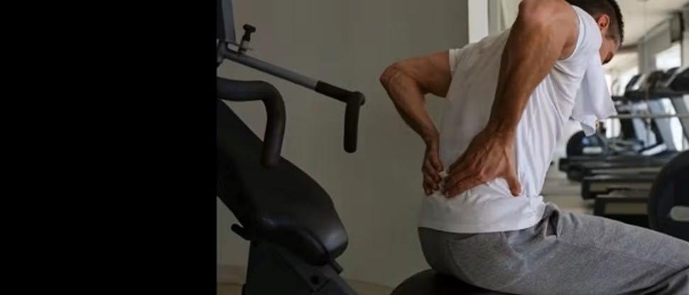 Hombre sujetándose la espalda baja con ambas manos