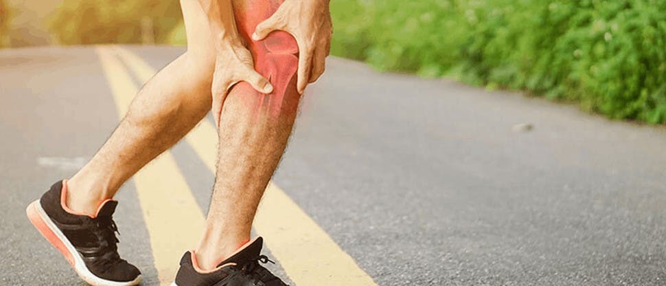 Persona tocándose la pierna que le duele