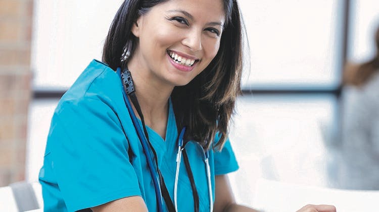 Image d’une médecin souriante portant une blouse bleu sarcelle