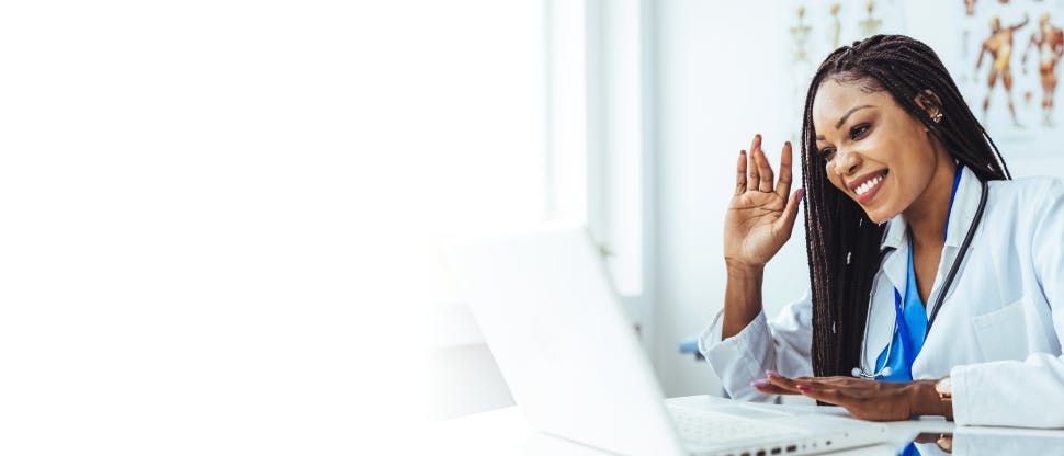 Une médecin travaillant sur un ordinateur portable dans un bureau d'hôpital, en appel vidéo.