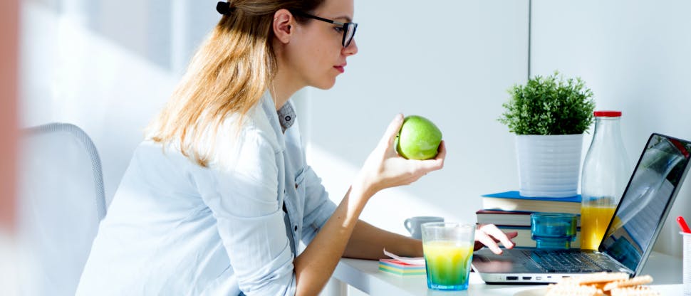Nutritionniste mangeant une pomme à son bureau