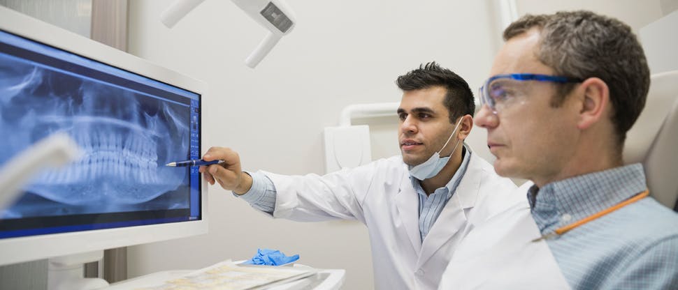 Praticien dentaire expliquant une radiographie à son patient