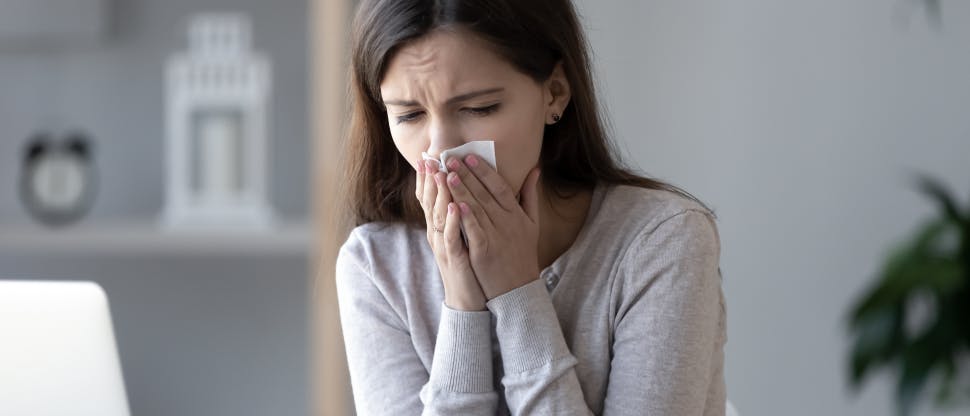 Femme qui se mouche et qui semble avoir des douleurs