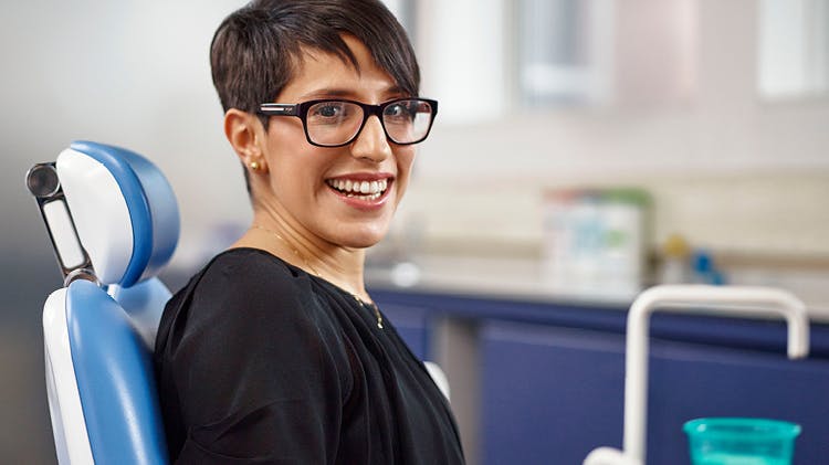 Dentiste professionnel avec des lunettes souriant à la caméra