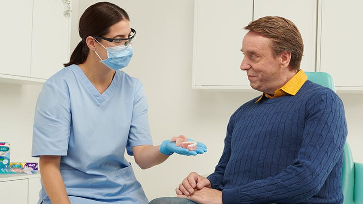 Dentiste discutant de prothèses dentaires avec un patient