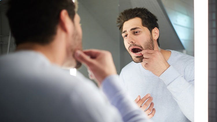 Image d'un homme regardant ses gencives dans un miroir