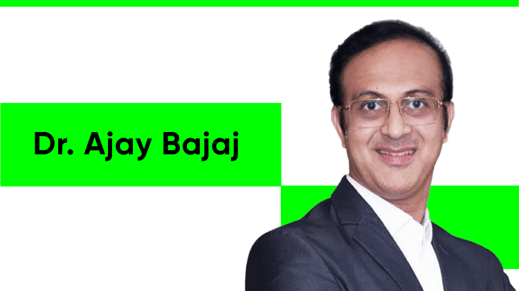 Portrait du Dr Ajay Bajaj, un homme asiatique aux cheveux courts et foncés. Il porte des lunettes, une chemise à rayures rouges et blanches et une veste noire.