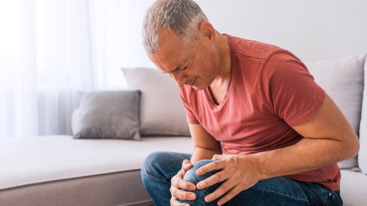 Férfi fogja a térdét