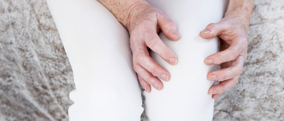 Nő fogja a térdét