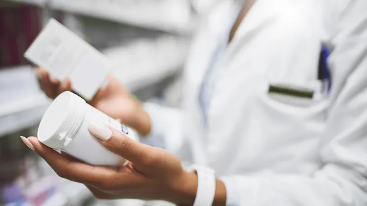 A young female pharmacist is checking through a prescription in the chemist.