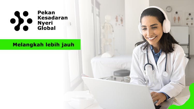 Dokter wanita bekerja di depan laptop di ruang kerja rumah sakit, mengetik, tersenyum, menggunakan headphone nirkabel untuk panggilan konferensi video.