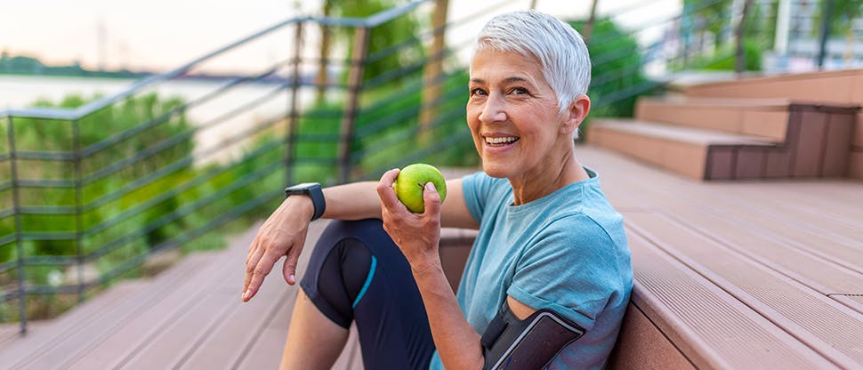 Elder woman sitting with an apple in a hand