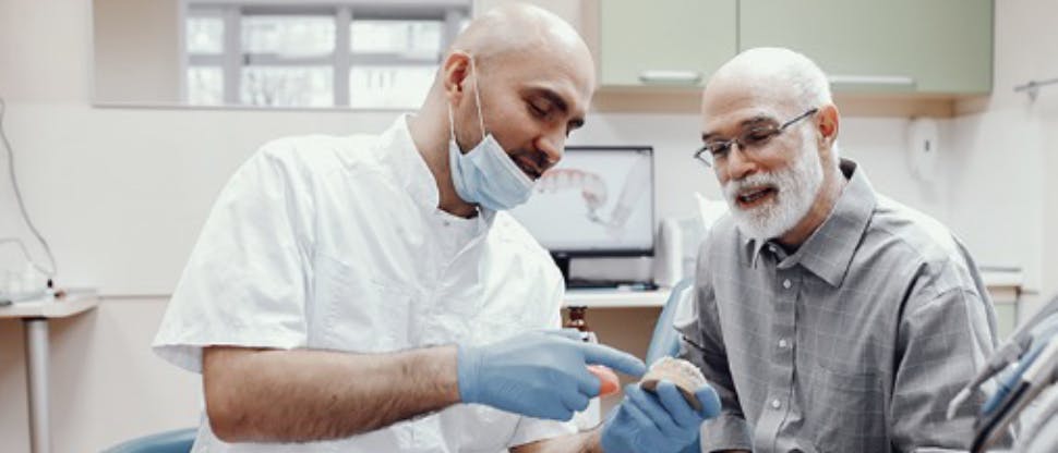Un dentista e un paziente guardano insieme un modello di bocca e di denti