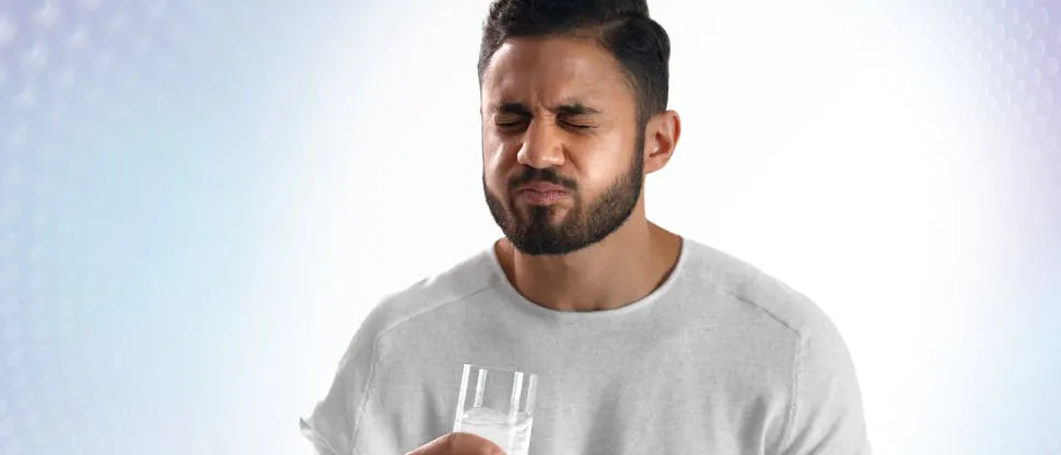 Immagine di un giovane paziente che beve acqua fredda e reagisce al dolore dei denti sensibili.