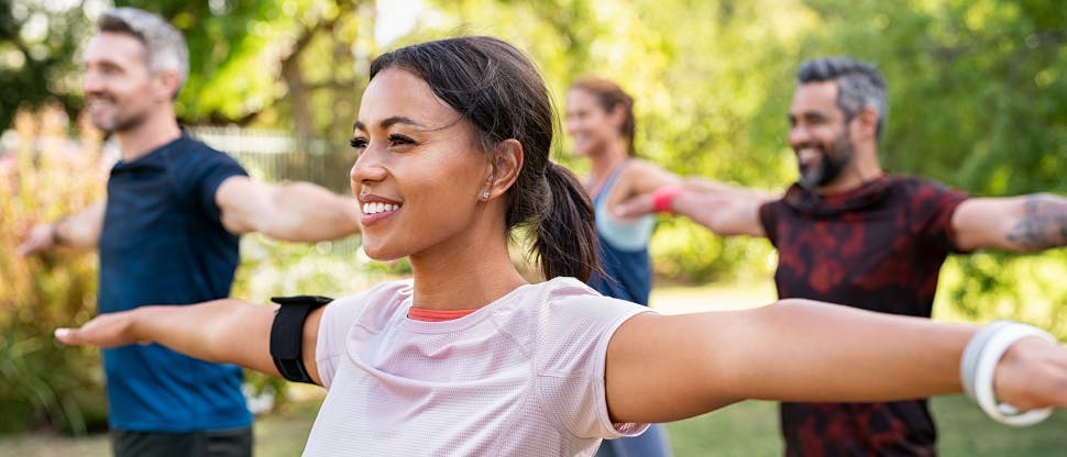 Zróżnicowana grupa ludzi ćwicząca na zewnątrz w słońcu
