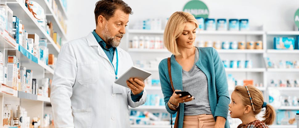 Dojrzały farmaceuta rozmawia z matką i córką w aptece