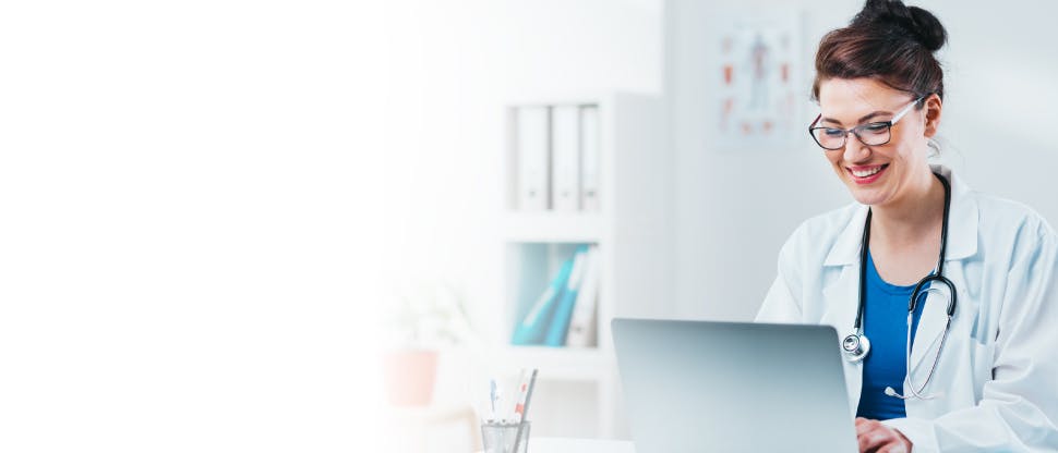 Medic care lucrează la laptop în biroul spitalului, care participă la un apel videoconferință