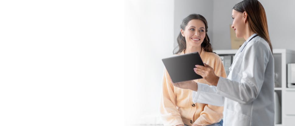 Un medic care ajută o pacientă care poartă un halat de spital cu exerciții fizice.