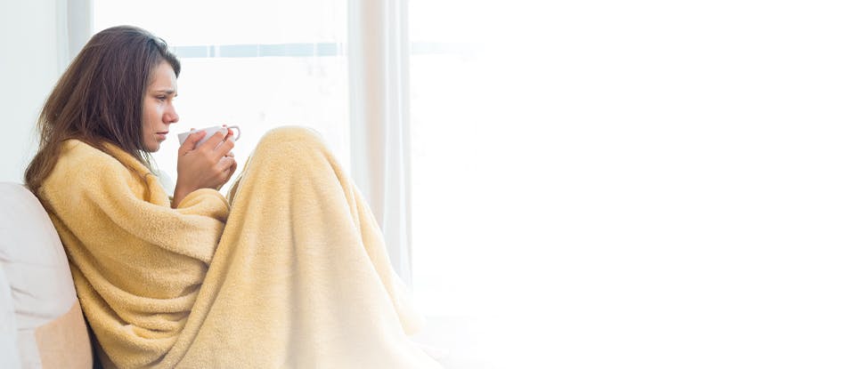 Femeie învelită în pătură care nu se simte bine