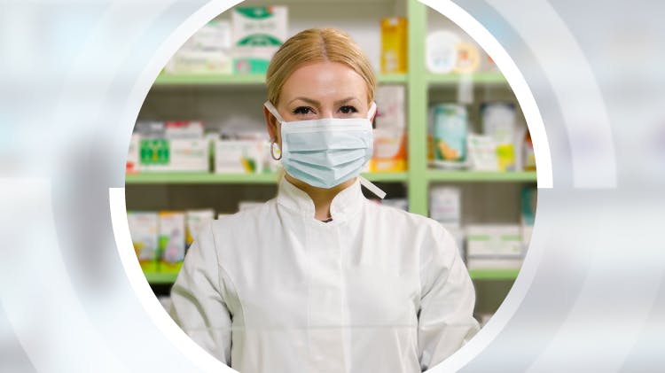 Работница аптеки носит лицевую маску, чтобы защитить себя от вируса COVID-19