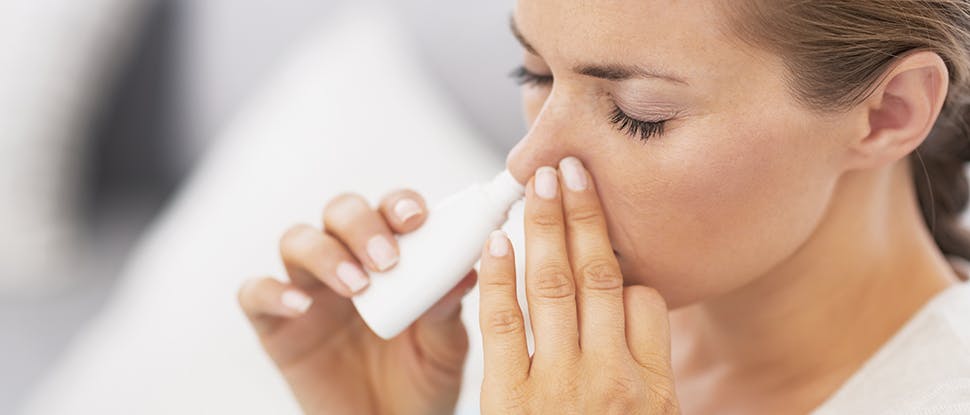 Женщина пользуется назальным спреем для уменьшения заложенности носа