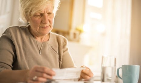 Een oudere vrouw leest een briefje dat zij in haar handen houdt