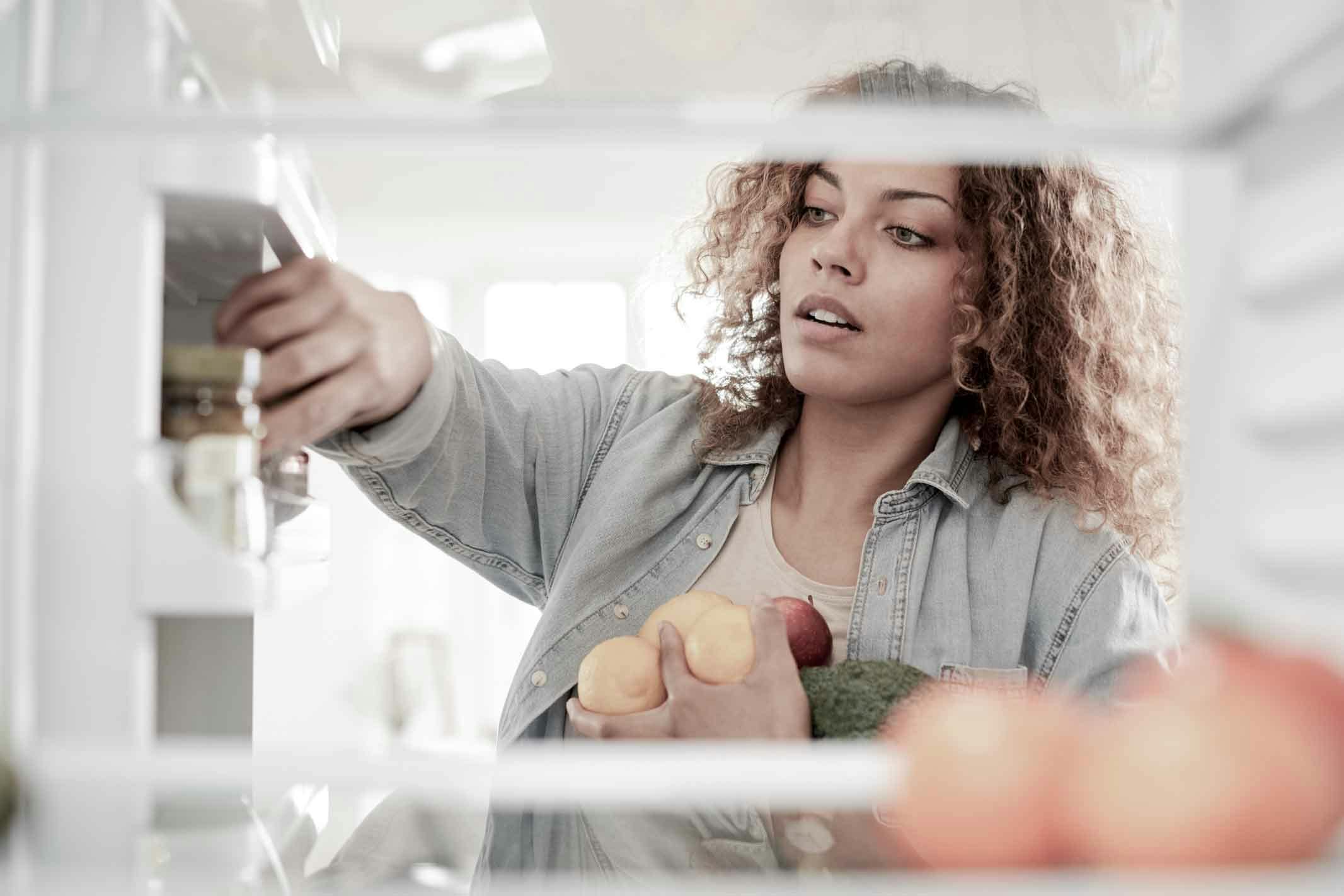 Kvinna som lagrar matvaror i kylskåp 