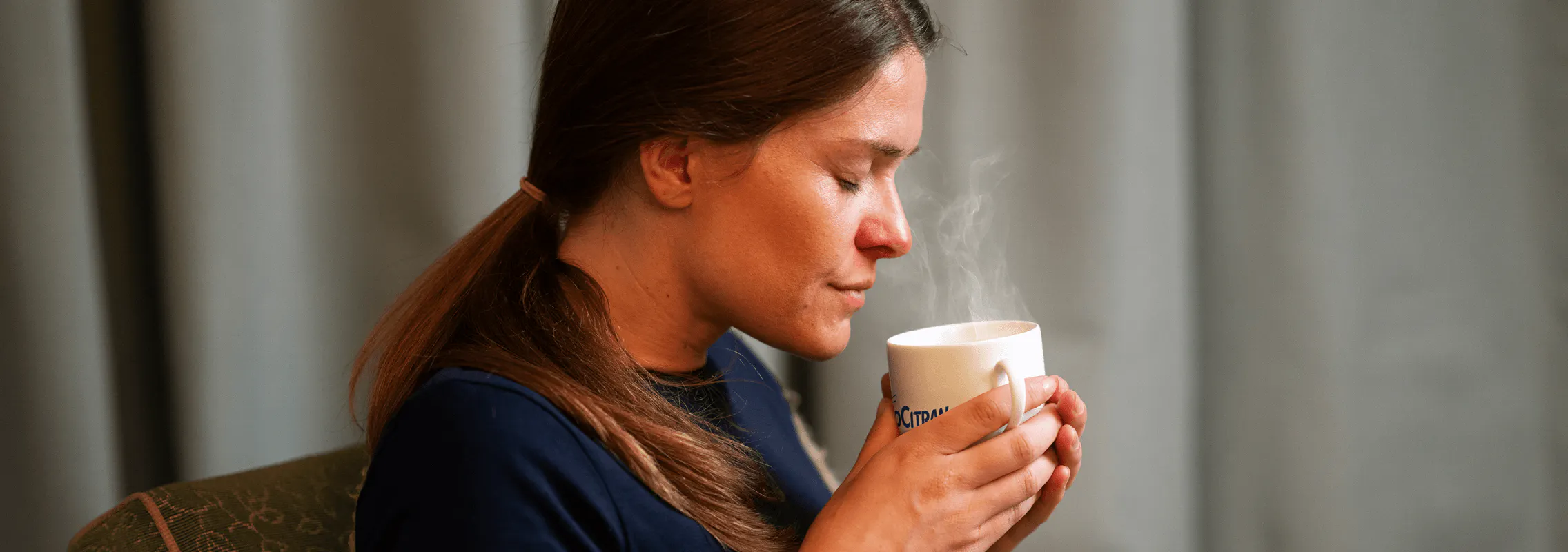 Femme qui tient une tasse fumante de NeoCitran
