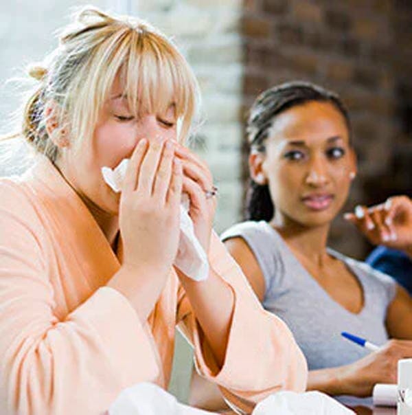 Woman sneezing around her friends