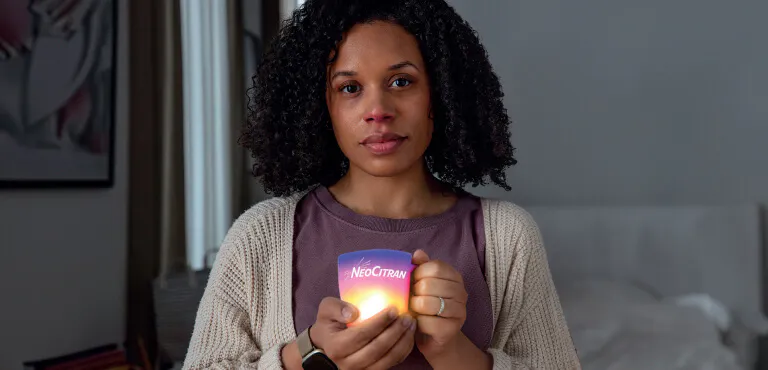 Woman with a cold holding a soothing cup of NeoCitran