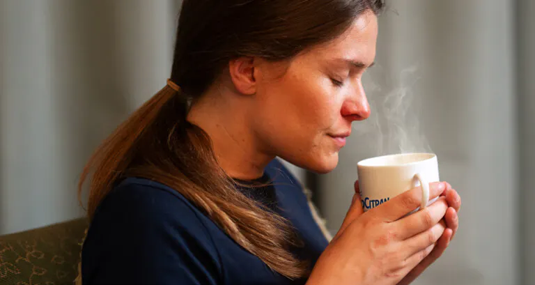 Woman holding a steaming mug of NeoCitran