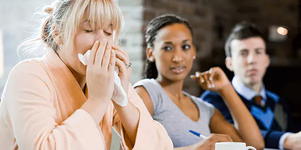 Woman sneezing around her friends