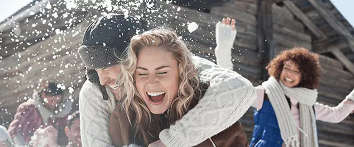 Couple s'étreignant et riant à l'extérieur dans la neige