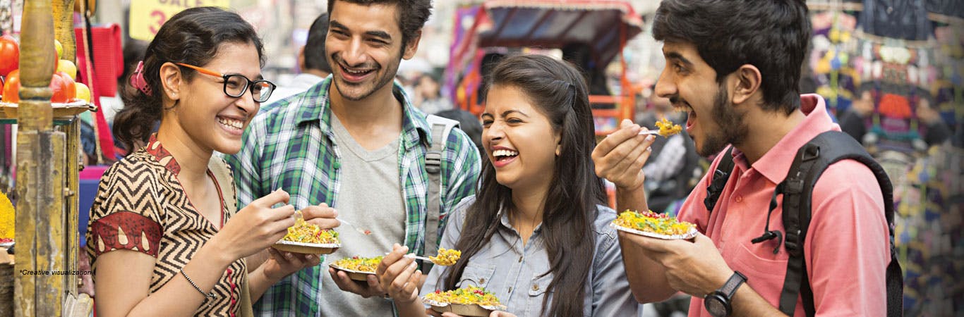 Young group of friends laughing and eating street food/chaat