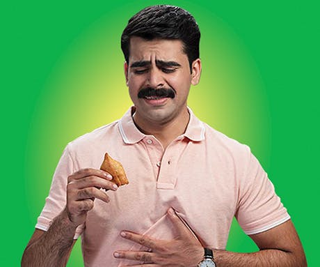 A man looking distressed while holding a samosa