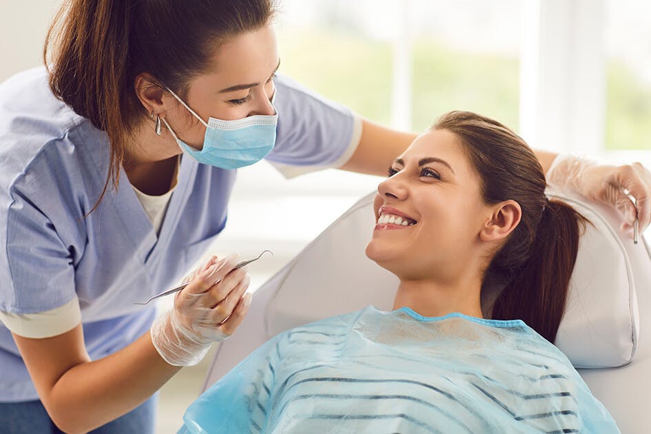 Female Dentist Conducting an Exam on a Smiling Female Patient Female Dentist Conducting an Exam on a Smiling Female Patient