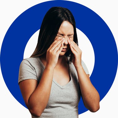 Eine Frau reibt ihre Nase wegen einer Nasennebenhöhlenentzündung, eine Entzündung die meist von einer Erkältung kommt