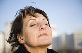 Older woman breathes deeply after probably cleaning her nasal passages of air pollutants with Otrivin Breathe Clean.
