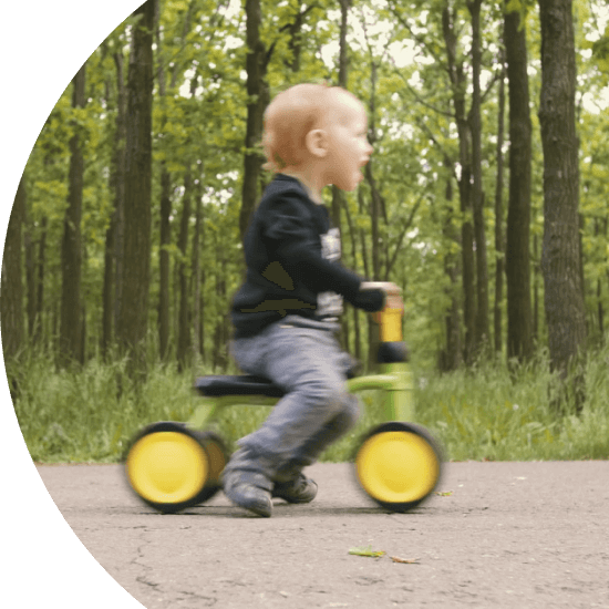 Toddler riding a tricycle through a forest