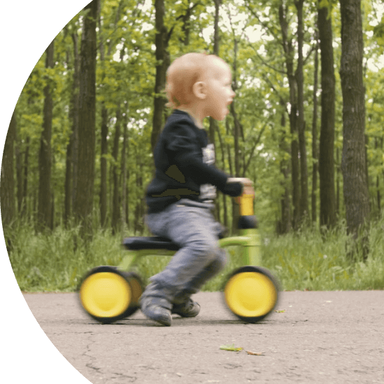 Toddler riding a tricycle through a forest 