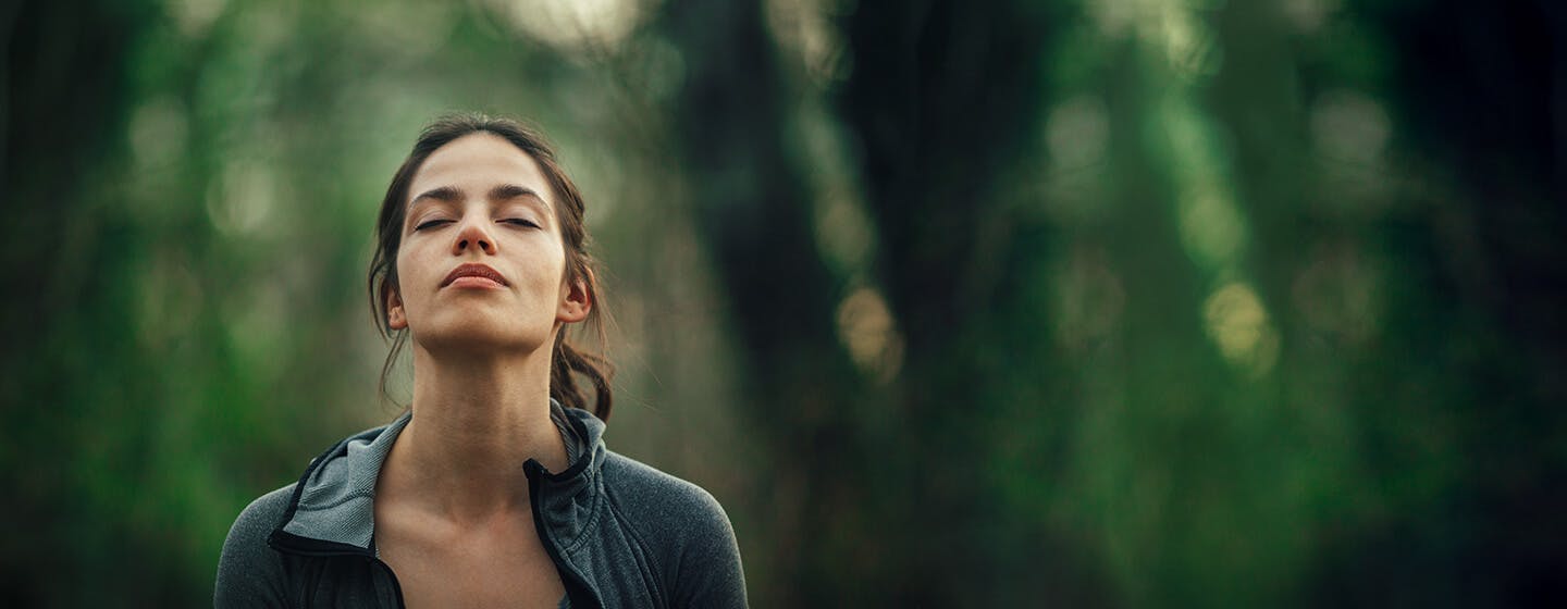 Woman breathes freely in a forest with a decongested nose.