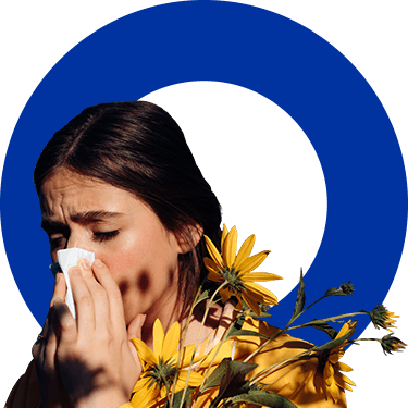 Woman blows her nose which can be a symptom of a cold, flu or allergies such as hay fever.