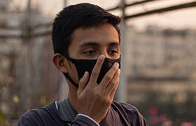 Asian boy wearing mask for protect pm2.5 and show stop hands gesture for stop corona virus outbreak