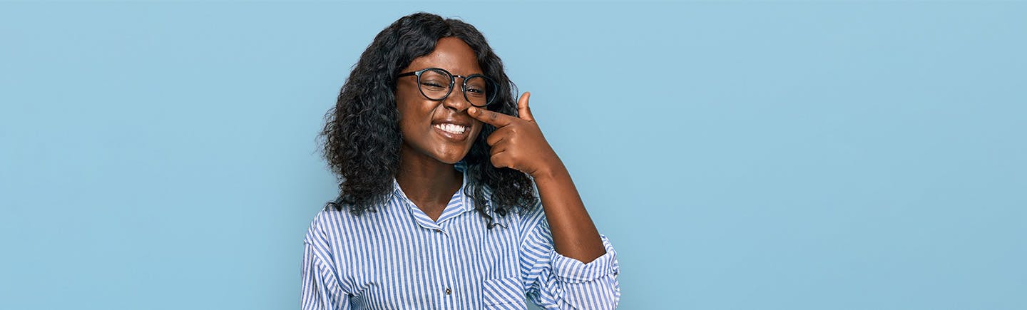 Young woman points to her nose, an organ  of the respiratory system that helps you breathe by filtering impurities from the air.